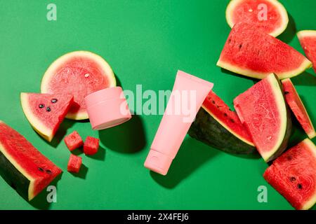 Szene für die Werbung für Kosmetik mit Wassermelonenscheiben und einem Satz kosmetischer Mockups auf grünem Hintergrund. Reich an Antioxidantien, Wassermelonen ist Stockfoto