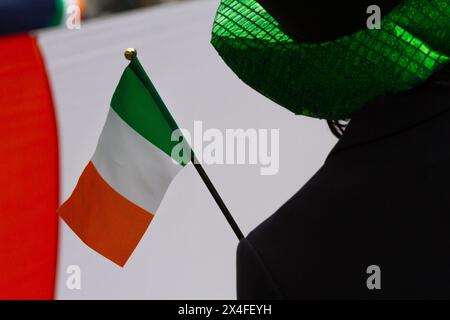 Eine Frau mit grünem Hut hält eine kleine irische Flagge während der 28. St. Patrick's Day Parade in Omotesando, Tokio, Japan. Stockfoto