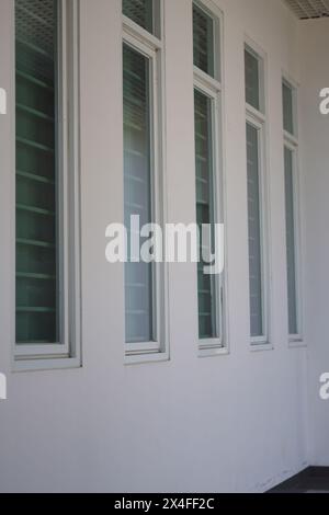 Fenster mit geschlossenen Vorhängen säumen die weißen Wände Stockfoto