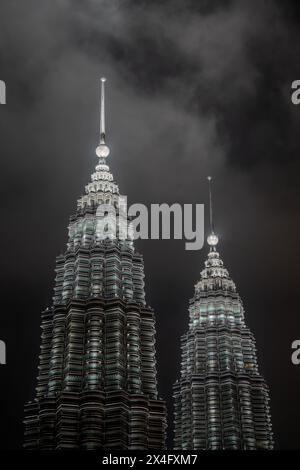 Das vertikale Bild zeigt die hoch aufragenden Silhouetten zweier legendärer Wolkenkratzer, die einen dramatisch bewölkten Himmel durchdringen. Die Türme sind beleuchtet, standi Stockfoto