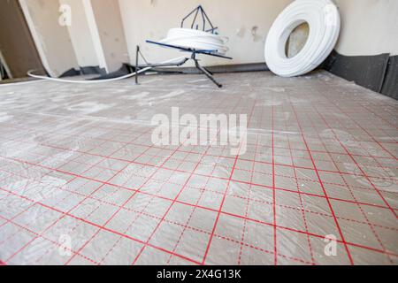 Ansicht auf geteilte Fläche, mit roten Hilfsleitungen, Gitter, zur Unterstützung bei der Platzierung der Rohrleitung der Fußbodenheizung in einem Wohngebäude unter dem Dach Stockfoto