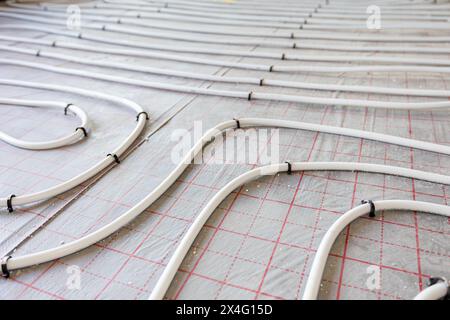 Niedriger Winkel auf dünne, weiße Röhren, die in komplexer Kurve gebogen sind, eines neuen Verteilersystems aus Messing, das für den Zentralheizungsboden in einer Residentia montiert ist Stockfoto