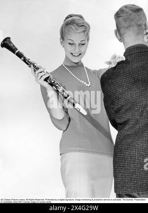 In den 1950er Jahren Eine junge Frau von vorne gesehen, die eine Klarinette hält, während ein Mann hinter der Kamera steht. 1956 Stockfoto