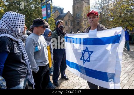 Während einer pro-palästinensischen Demonstration auf dem Campus der Melbourne University schwingt ein Gegenprotestierender eine israelische Flagge auf Demonstranten. Der pro-israelische trägt eine Make America Great Again-Mütze. Melbourne, Victoria, Australien. Stockfoto