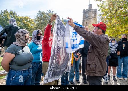 Während einer pro-palästinensischen Demonstration auf dem Campus der Melbourne University schwingt ein Gegenprotestierender eine israelische Flagge auf Demonstranten. Der pro-israelische trägt eine Make America Great Again-Mütze. Melbourne, Victoria, Australien. Stockfoto