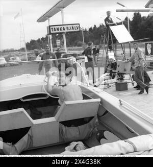 ESSO-Tankstelle im Jahr 1963. Die Firma Svenska Esso war eine Marke in Schweden zwischen 1939 und 1987, als die Bahnhöfe ihren Namen in den Namen des neuen Eigentümers Statoil änderten. An der Tankstelle wird ein Werbespot gefilmt, in dem ein Motorboot neben den Gaspumpen steht und eine junge Frau am Lenkrad gesehen wird. Kristoffersson Ref. DC135-12 Stockfoto