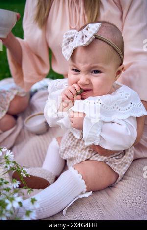 Das kleine Mädchen isst Trauben in den Armen ihrer Mutter Stockfoto