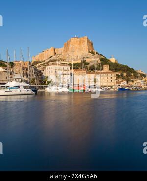 Bonifacio, Corse-du-Sud, Korsika, Frankreich. Blick über den Hafen auf die Zitadelle, Sonnenaufgang, die Bastion de l'Etendard, die über den Gebäuden am Ufer thront. Stockfoto