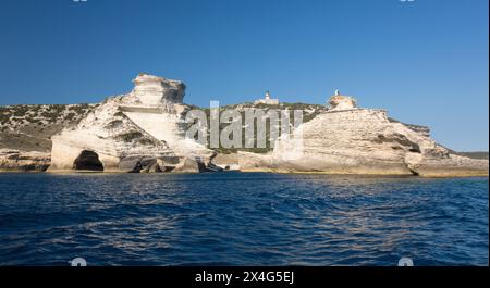 Bonifacio, Corse-du-Sud, Korsika, Frankreich. Blick vom Meer auf den Leuchtturm und die zerklüfteten Kalksteinklippen von Capo Pertusato. Stockfoto