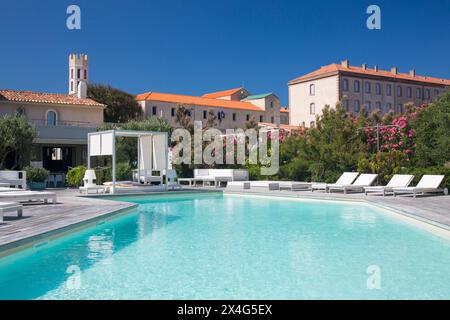 Bonifacio, Corse-du-Sud, Korsika, Frankreich. Blick über den Swimmingpool des Hôtel Genovese, Turm der Eglise Saint-Dominique, sichtbar im Hintergrund. Stockfoto