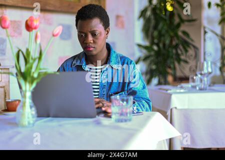 Fokussierte junge afroamerikanische Frau benutzt Laptop im Café Stockfoto