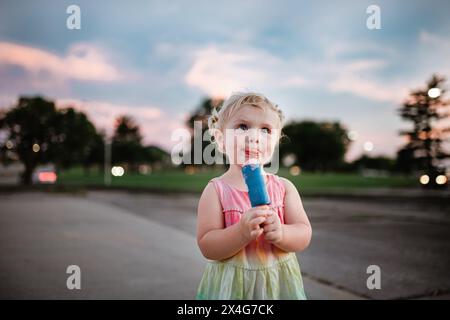 Das junge Mädchen isst Eis an einem warmen Sommerabend Stockfoto