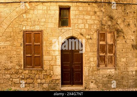 Die Fassade eines alten Steinhauses mit einer Holztür auf der Mittelmeerinsel Rhodos Stockfoto