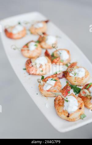 Gegrillte Garnelenspieße mit Kräutern und Sahnesauce Stockfoto