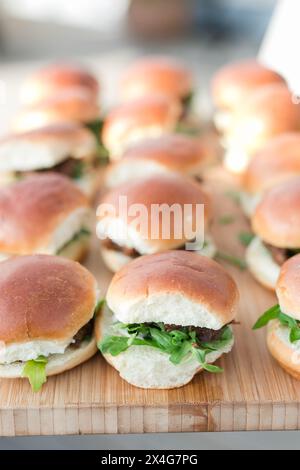 Goldene Mini-Burger mit Rucola auf einem hölzernen Serviertablett Stockfoto