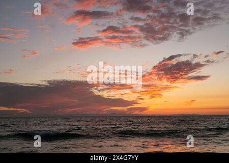 Lebendiger Sonnenuntergang mit feurigen Wolken über dem Ozean Stockfoto