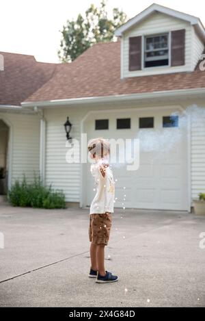 Kleiner Junge mit Sparkler vor der Garage im Sommer Stockfoto