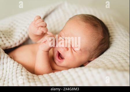 Säuglingsneugeborenes Baby, das zu Hause in weicher Decke gähnt und schläft Stockfoto