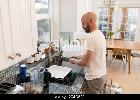 Mann, der Geschirr in der Küche ausspült Stockfoto