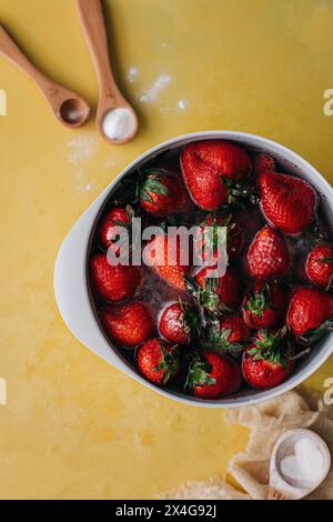 Gewaschene Erdbeeren in einer weißen Schüssel mit Natron und Holz Stockfoto