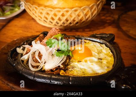 Bo ne trung, Rindfleisch auf einer heißen Platte mit Soße und Eiern, vietnamesisches Frühstück. Bo ne, ein traditionelles vietnamesisches Frühstück mit Steak, Eiern und bague Stockfoto