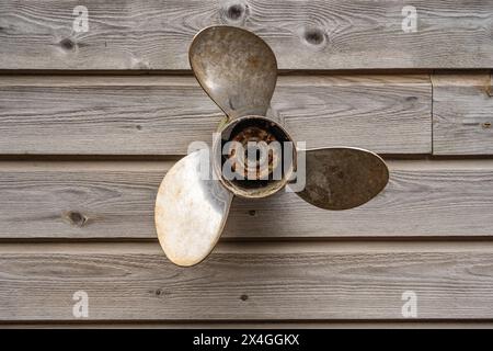 Verwitterter Propeller hängt an einer Holzwand Stockfoto