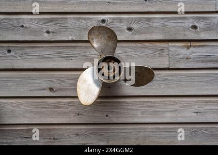 Verwitterter Propeller hängt an einer Holzwand Stockfoto