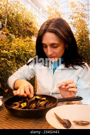 Südisland-2. märz 2023: kaukasische Touristenfrau isst Muscheln in Fridheimar - Besucherfreundliche Tomatenfarm und Restaurant in Fridheimar Stockfoto