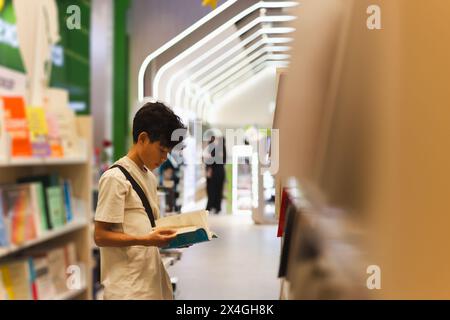 Junge, der in einem Buchladen Buch liest. Stockfoto