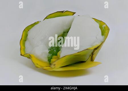 Nahaufnahme einer grünen Sagopalme mit Zuckermais in einem Khanom Tako Thai Kokospudding Dessert, in einem gefalteten Pandanblatt Becher Stockfoto