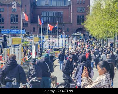 Amsterdam Niederlande 21 April 2024, Eine lebhafte Szene entfaltet sich, während eine große Gruppe von Menschen aus unterschiedlichen Hintergründen durch eine lebhafte Stadtstraße zieht Stockfoto