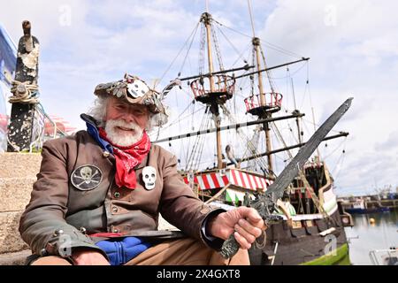 Brixham, Großbritannien. Mai 2024. An einem warmen Tag in Brixham in Devon wird Terry auf den Stufen mit dem Golden Hind Museum Schiff hinter sich gesehen. Bildnachweis: Robert Timoney/Alamy Live News Stockfoto