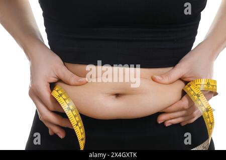 Frau mit Maßband, das Bauchfett auf weißem Hintergrund berührt, Nahaufnahme. Problem mit Übergewicht Stockfoto