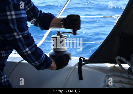 Der Mann dreht eine Yachtkurbel an der Segelbootswinde, Yachtdetails. Yachting Stockfoto