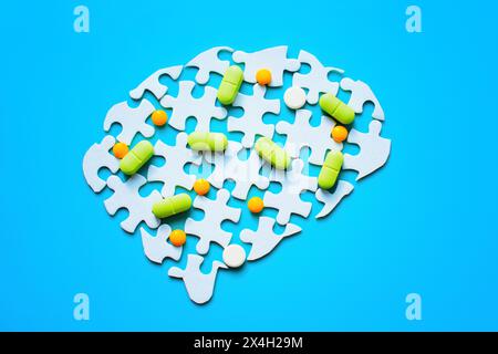 Zerlegtes Puzzle in Form eines Gehirns. Puzzleteile werden getrennt und bunte Pillen darüber verteilt. Psychische Gesundheit, Mediziner Stockfoto