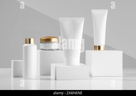 Weiße Kosmetikprodukte für Gesicht und Körper auf weißen Würfeln Stockfoto