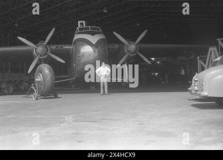 England um 1957 – Ein Foto des Dan Air Bristol Typ 170 Frachters Mk.31E, Kennzeichen G-AINL, geparkt in einem Wartungshangar. Dieses Flugzeug mit der Seriennummer 012827 wurde 1947 von der Bristol Aeroplane Company Ltd hergestellt. Dan Air erhielt es im Juli 1957 von der Aviation Traders Ltd, die zuvor bei der Royal Air Force und Aer Lingus gedient hatte. Es war die erste von drei seiner Art, die bei Dan Air in Dienst gestellt wurden. Ein Mann steht vor dem Flugzeug und ein Ersatzflugzeugrad befindet sich auf einem Trolley im Vordergrund. Stockfoto