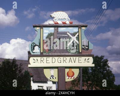 Suffolk. 1987: Ein Foto des Dorfzeichens von Redgrave in Suffolk, England. Das Schild ist handgefertigt aus geschnitztem Holz und mit lokalen Wahrzeichen und Motiven dekoriert. Redgrave liegt etwa 4,5 km westlich der Stadt DISS und südlich des Flusses Waveney, der die Grenze zu Norfolk bildet. Stockfoto