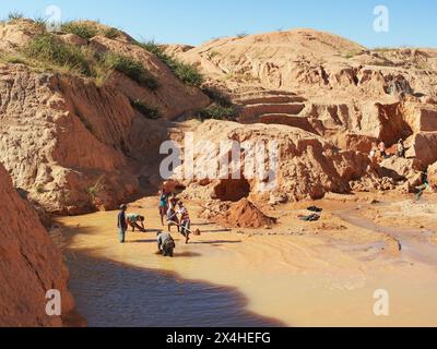 Ilakaka, Madagaskar - 30. April 2019: Gruppe unbekannter madagassischer Männer, die an einem sonnigen Tag mit Schaufeln Saphir in der oberflächennahen Seegrube abbauen, trockener roter Boden Stockfoto