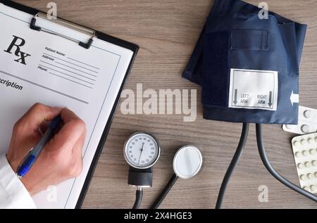 Konzept der Überwachung der Herzgesundheit und des Blutdrucks mit dem Arzt, der Medikamente auf einem Holztisch verschreibt. Draufsicht. Stockfoto