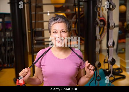 Porträt einer lächelnden Frau mittleren Alters in Sportbekleidung mit Seilspringen Stockfoto