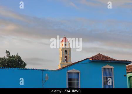 235 der Glockenturm der Kirche Iglesia de San Francisco de Asis über einem blauen Kolonialhaus auf dem Plaza Mayor Square am späten Nachmittag. Trinidad-Kuba. Stockfoto