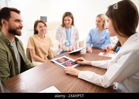 Gynäkologe zeigt Kollegen und Paarergebnisse eines Schwangerschaftsscans Stockfoto