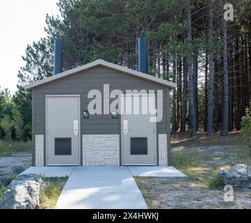 Moderne öffentliche Einrichtungen im Freien mit neuen Toiletten für Männer, Frauen und Behinderte in einem Park in der Nähe von Bäumen. Gehsteig aus Beton und große Felsbrocken in der Nähe von t Stockfoto