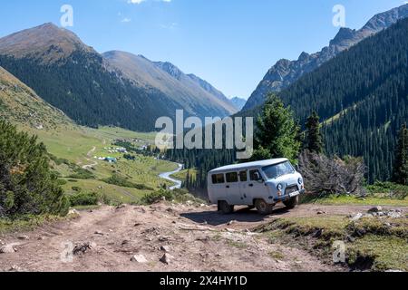 UAZ Buchanka, russisches Geländefahrzeug auf Geländewagen, grünes Bergtal mit Dorf Altyn Arashan, Tien Shan Berge, Kirgisistan Stockfoto