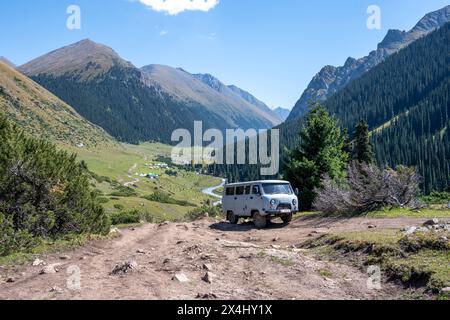 UAZ Buchanka, russisches Geländefahrzeug auf Geländewagen, grünes Bergtal mit Dorf Altyn Arashan, Tien Shan Berge, Kirgisistan Stockfoto