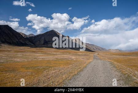 Schotterpiste auf Plateau, dramatische hohe Berge, Tian Shan Berge, Jety Oguz, Kirgisistan Stockfoto