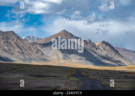 Schotterpiste auf Plateau, dramatische hohe Berge, Tian Shan Berge, Jety Oguz, Kirgisistan Stockfoto