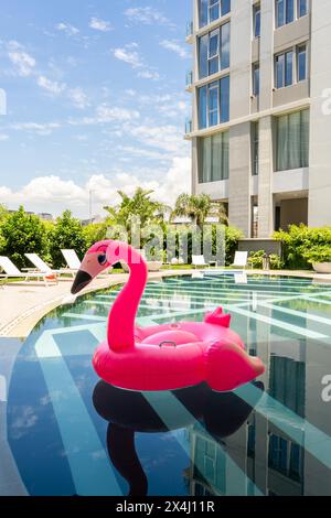 Ein rosafarbener Flamingoschwimmer schwimmt in einem Pool. Vertikale Aufnahme Stockfoto