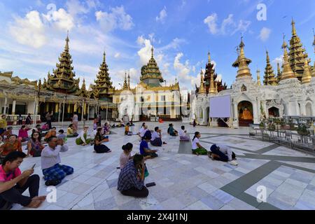 Shwedagon-Pagode, Yangon, Myanmar, Asien, eine Gruppe von Menschen, die auf dem Boden sitzen und gemeinsam an einem heiligen Ort beten Stockfoto